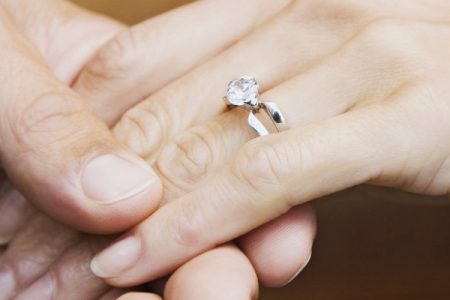 Couple holding hands with engagement ring