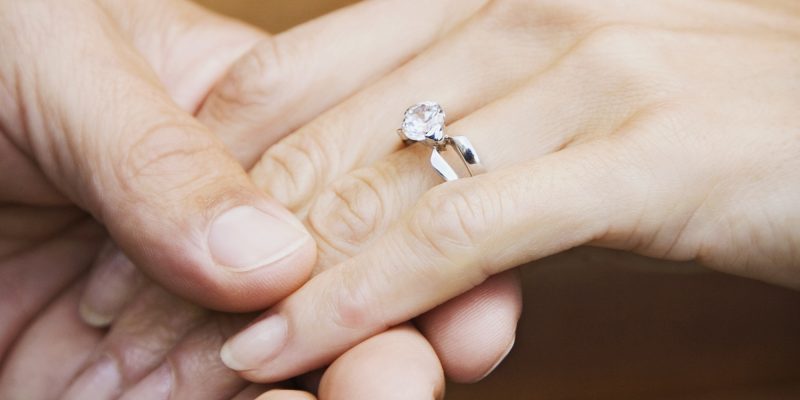 Couple holding hands with engagement ring